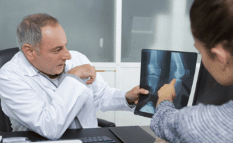 Provider reviewing a digital knee X-ray with a patient during an urgent care X-ray visit.